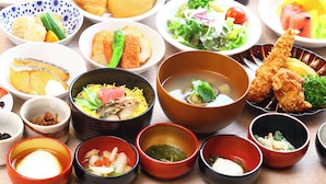 A variety of dishes including sushi, sashimi, and other Asian cuisine, arranged on a table.