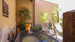 Een bubbelbad met een waterval, omringd door stenen muren en potplanten.