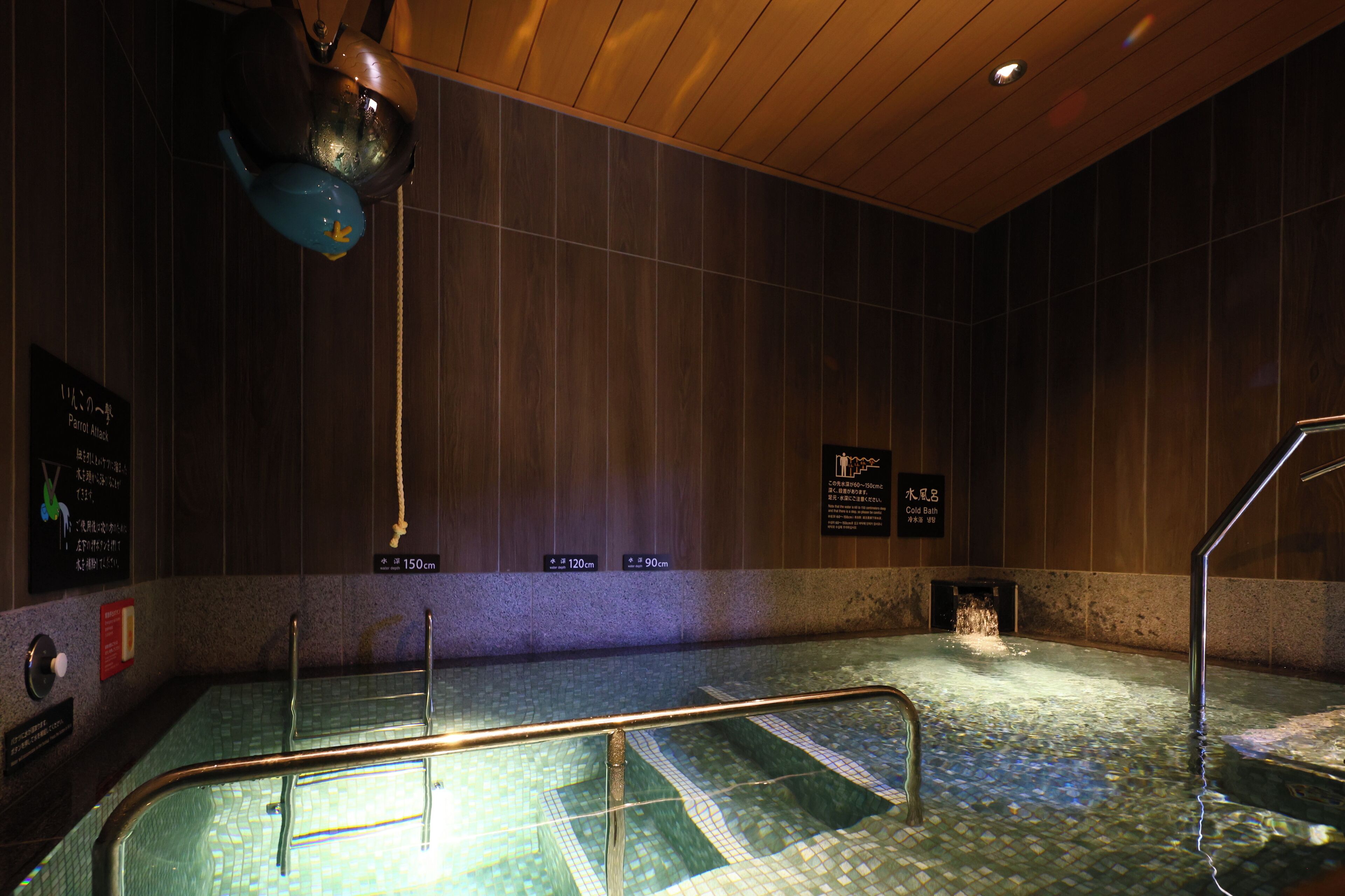 A hot tub area with tiled walls, a wooden ceiling, and a metal railing.