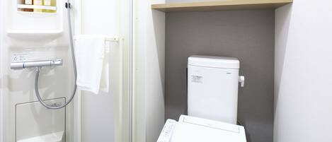 Un baño con inodoro, ducha y repisa con artículos de aseo.