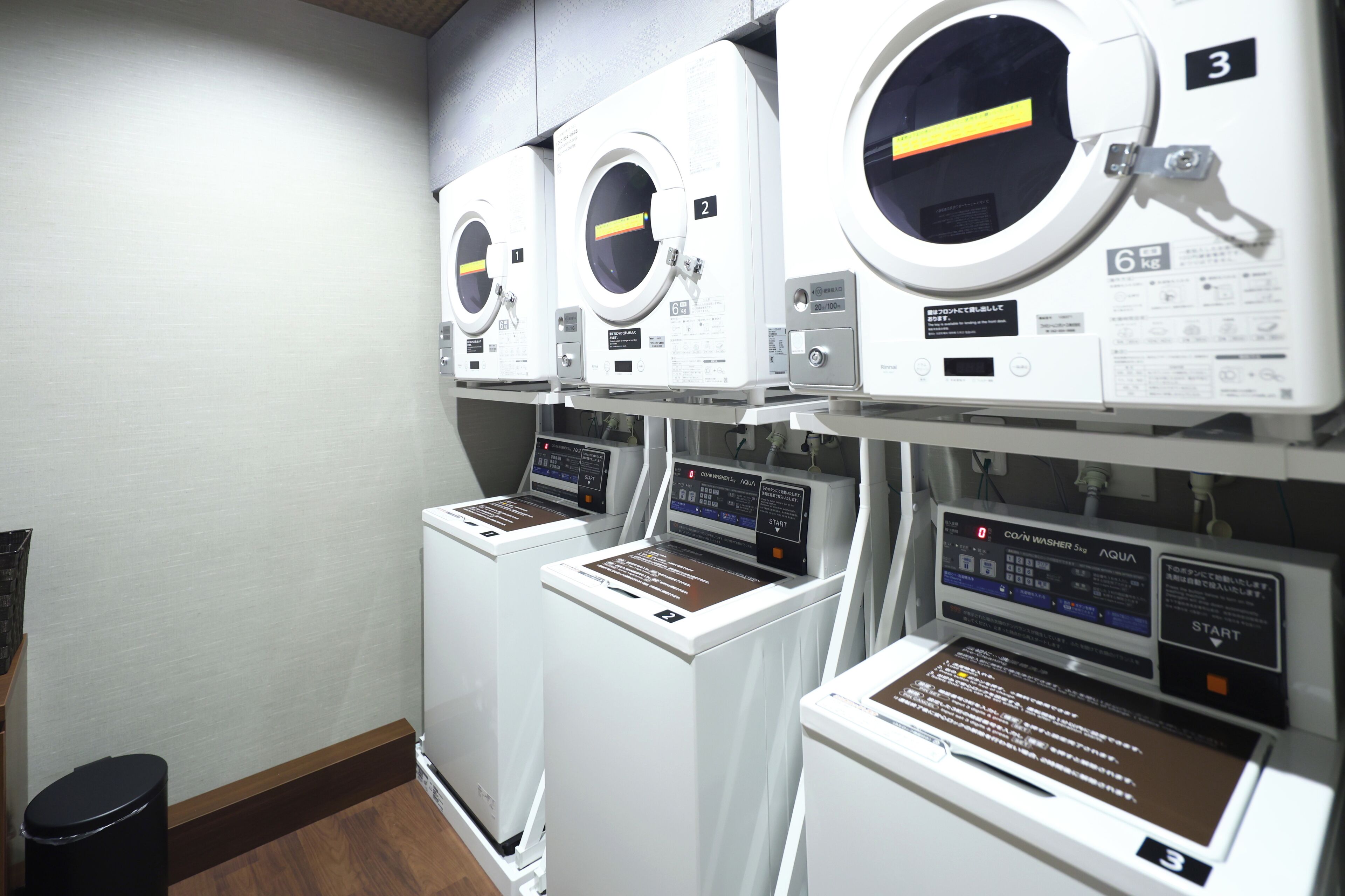 A row of front-loading washing machines in a commercial setting.