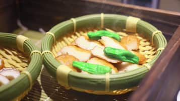 Um prato tradicional japonês com cestos de bambu, vegetais verdes e fatias de peixe.