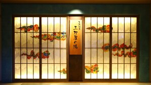 Een traditionele Japanse kamer met tatami vloeren, shoji schermen met bloemmotieven en een houten bord met Japanse tekens.