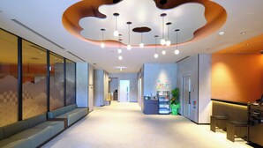 Een moderne hotel lobby met een uniek plafondontwerp, zithoeken en een receptiebalie.