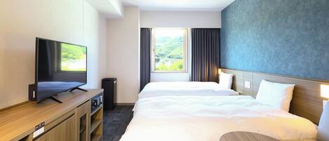 Ein Hotelzimmer mit Bett, Fernseher, kleinem Tisch und einem Fenster mit Vorhängen.