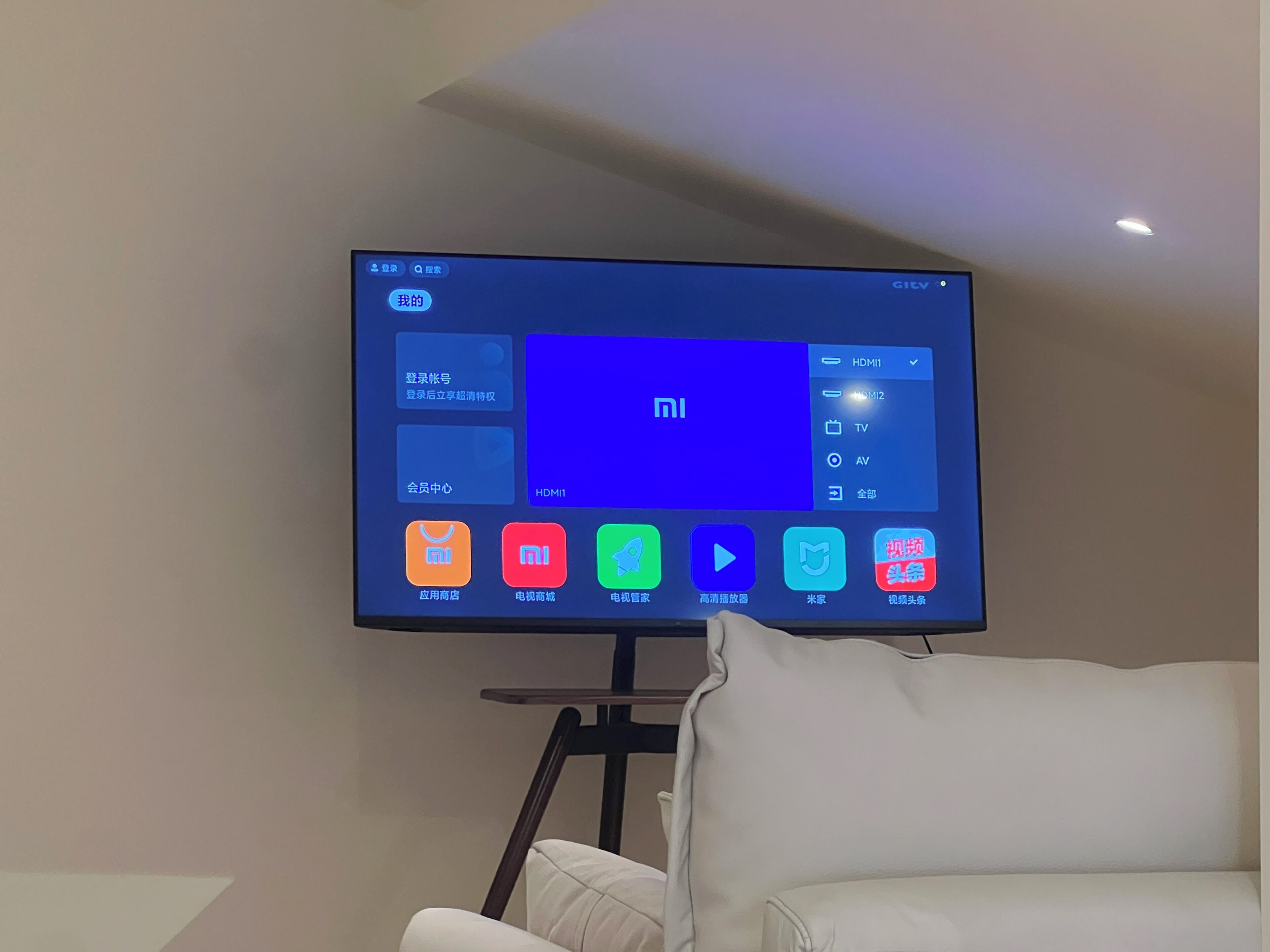 A flat-screen TV mounted on a stand against a wall, displaying a user interface with various app icons.