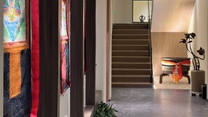 A modern interior with a staircase, a decorative wall, and a plant. - Harmony Zen Retreat in Jiuzhai Valley (Ngawa Autonomous Prefecture)