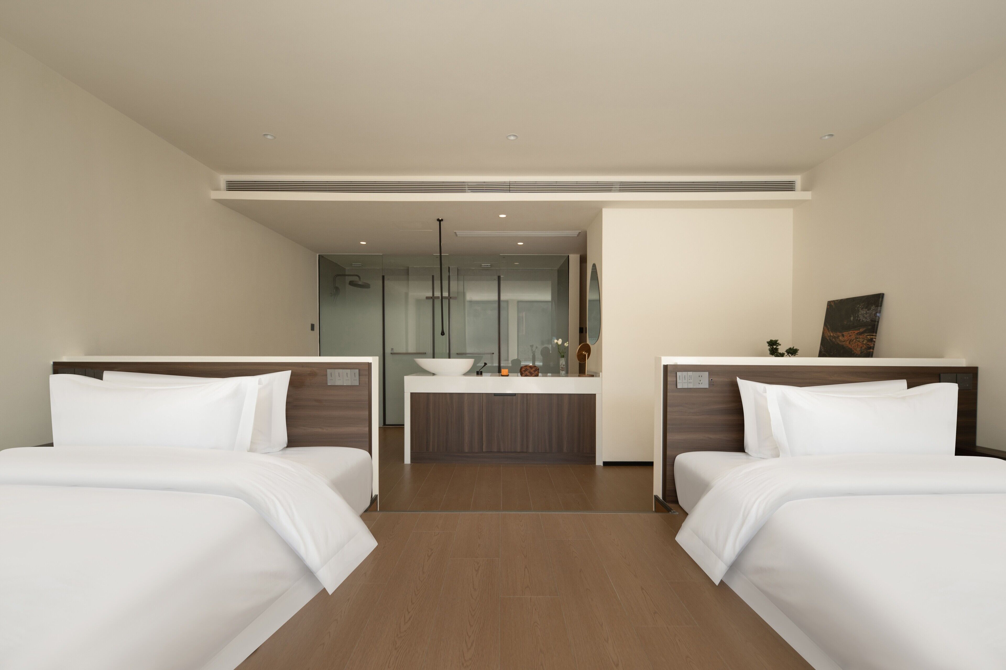 A hotel room with two beds, a central bathroom, and a view of the city.