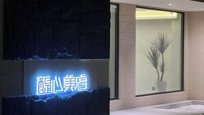 A modern building facade with a neon sign, a large window with a plant, and a stone wall. - Harmony Zen Retreat in Jiuzhai Valley (Ngawa Autonomous Prefecture)