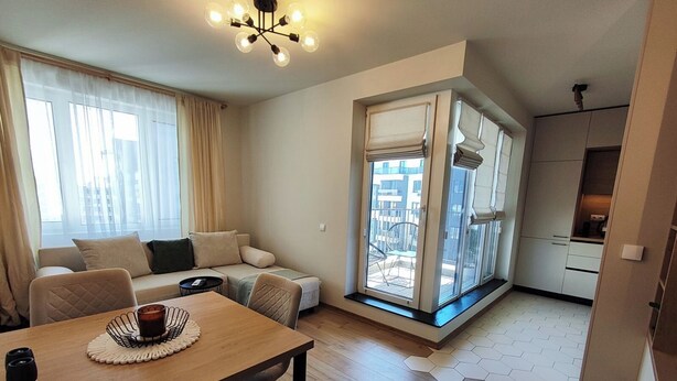Uma sala de estar moderna com uma mesa de jantar de madeira, um sofá e vista para a cidade através de grandes janelas.