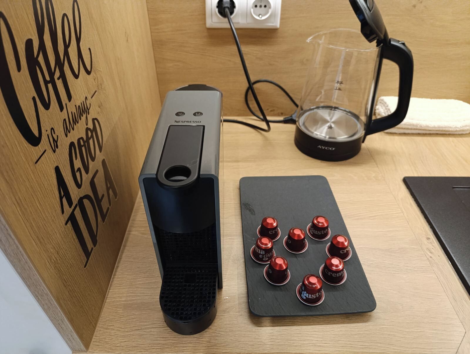 Une machine à café, une verseuse en verre et un moulin à café, le tout posé sur une table en bois.