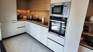 Uma cozinha moderna com armários brancos, bancada de madeira e forno embutido.