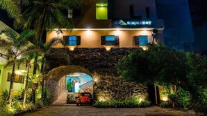 A hotel entrance with a stone archway, a red car parked in front, and a sign reading "ROCKFORT". - Rock Fort Beach Resort (Unawatuna)