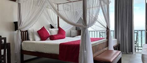 A bed with a canopy, a bench, and a view of the sea.