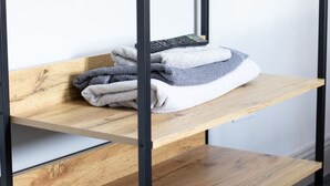 Uno scaffale in legno con asciugamani piegati e un telecomando.
