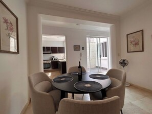 A dining area with a round table, four chairs, and a bottle of wine.