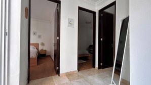 Un pasillo con dos habitaciones, cada una con cama y mesita de noche.