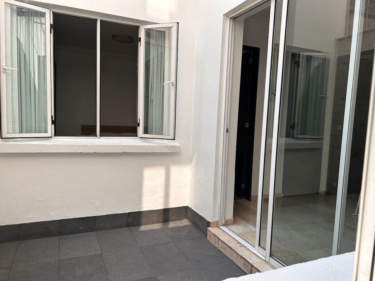 Une pièce dotée d’une porte-fenêtre coulissante, d’une fenêtre avec des rideaux et d’un plancher carrelé.