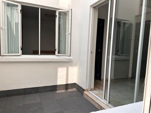 Une pièce dotée d’une porte-fenêtre coulissante, d’une fenêtre avec des rideaux et d’un plancher carrelé.