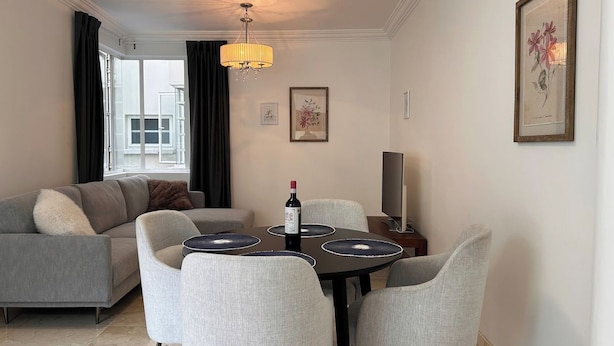 Una sala moderna con comedor, un sofá, un televisor y obras de arte en las paredes.