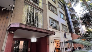 Un edificio de varios pisos con entrada cubierta, zona de estar al aire libre y balcones visibles.