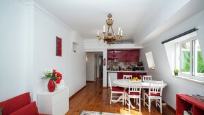Une cuisine moderne avec des meubles blancs, une table à manger entourée de chaises blanches et un lustre.