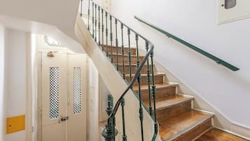 Escada com balaústres verdes e degraus de madeira que levam a um patamar.