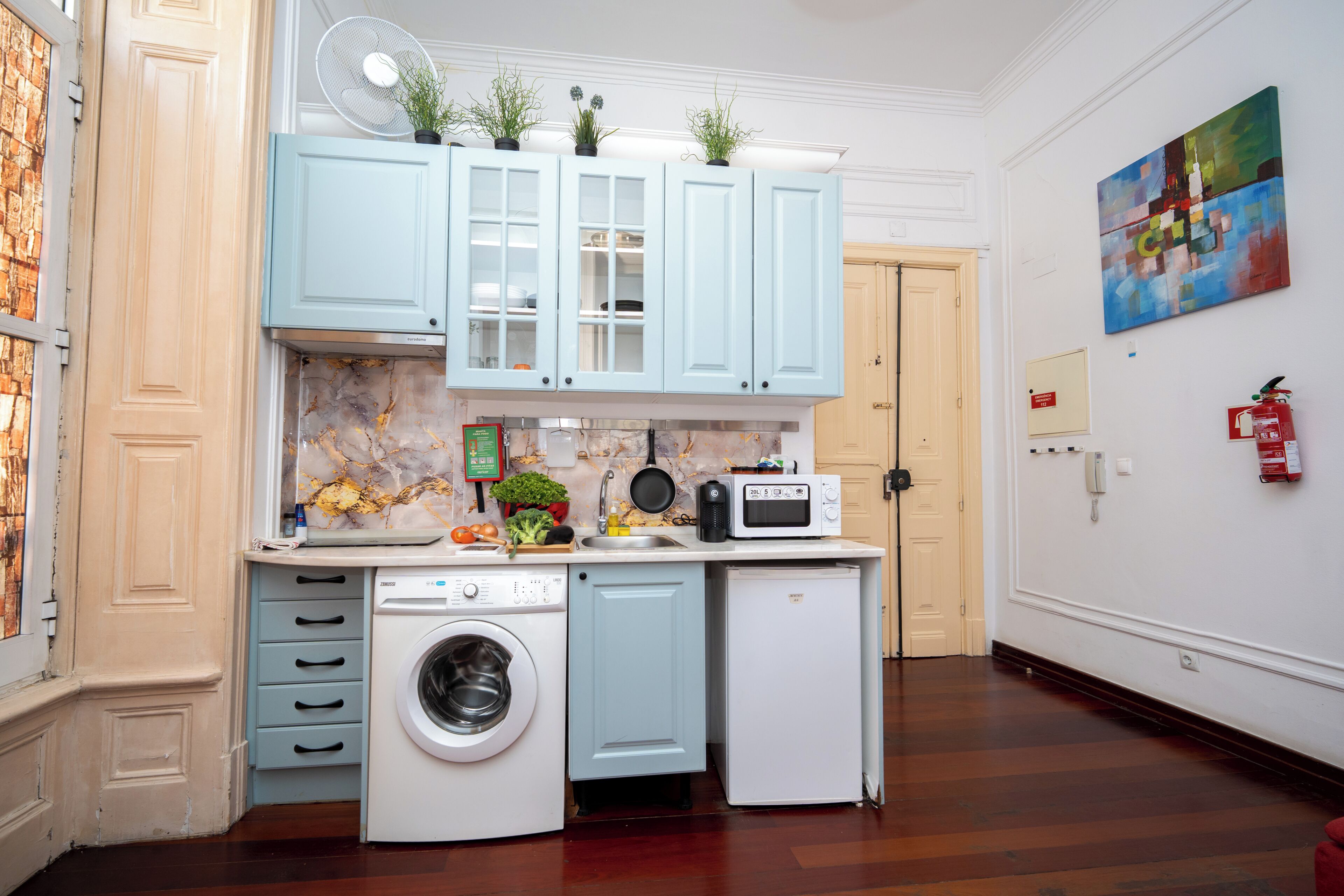 A compact kitchen with a washing machine, microwave, and cabinets.