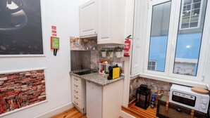 A compact kitchen with white cabinets, a granite countertop, a small refrigerator, and a microwave. - 2 Bedroom Apartment Located Heart of Lisbon City (Lisbon)