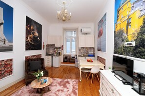 Una cucina moderna con mobili bianchi, una zona pranzo con tavolo e sedie, e un soggiorno con divano e tavolino.