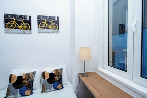 Una camera da letto con un letto, due cuscini, un comodino, una lampada e due quadri appesi al muro raffiguranti una bicicletta.