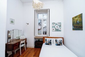Une chambre à coucher comprenant un lit, une commode, un miroir, une fenêtre et des œuvres d’art mural.