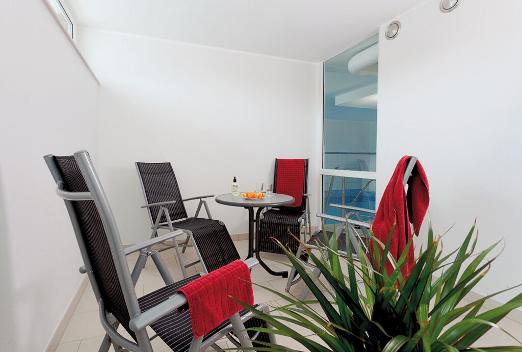 Un petit balcon avec une table, des chaises et un pot de fleurs.