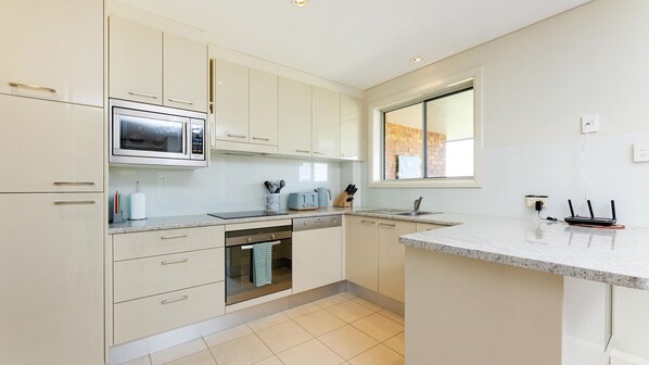 A modern kitchen with white cabinetry, a microwave, a toaster, and a dishwasher.