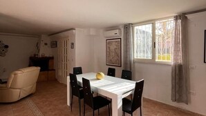 En rummelig opholdsstue med spisebord, stole, sofa og et køkken.