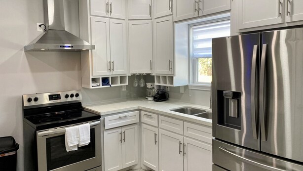 A modern kitchen with white cabinets, stainless steel appliances, and a window providing natural light.