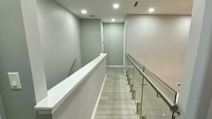 A modern, well-lit hallway with a glass railing and a white counter.