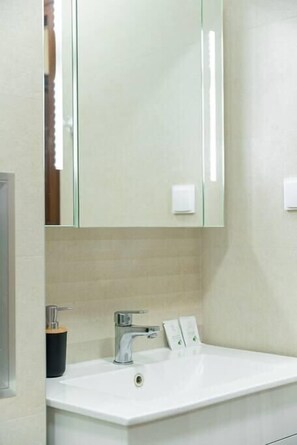 A modern bathroom with a white sink, a mirror, and a towel dispenser. - The BizHub | FREE Gym Pass | Center (Plovdiv)