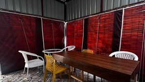 A room with a large wooden table, white and yellow chairs, and patterned floor tiles. - Sunita Residency (Gurugram)