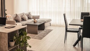Een moderne woonkamer met een bank, salontafel en eettafel.