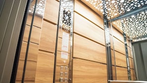 Een liftinterieur met houten lambrisering en een metalen handrail.