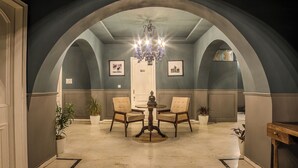 A room with a round table and two chairs, a chandelier, and framed pictures on the walls. - Victoria Mansion - A Signature Collection by HST Hotels (Udaipur)