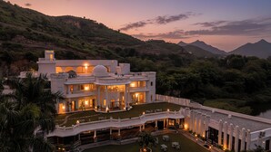 A large, multi-story building with a spacious courtyard, surrounded by lush greenery and mountains. - Victoria Mansion - A Signature Collection by HST Hotels (Udaipur)