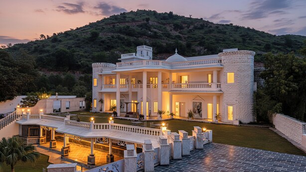 A large, multi-story building with a grand entrance, a spacious courtyard, and a view of a hilly landscape. - Victoria Mansion - A Signature Collection by HST Hotels (Udaipur)