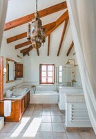 Un baño espacioso con un ventanal grande, techo de madera y una zona de ducha moderna.
