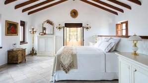 A bedroom with a large bed, wooden beams, a mirror, a dresser, and a window. - La Esperanza Granada (El Valle)