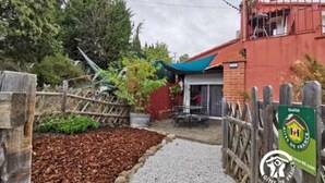 A rustic outdoor area with a wooden fence, a gravel path, and a small garden bed.