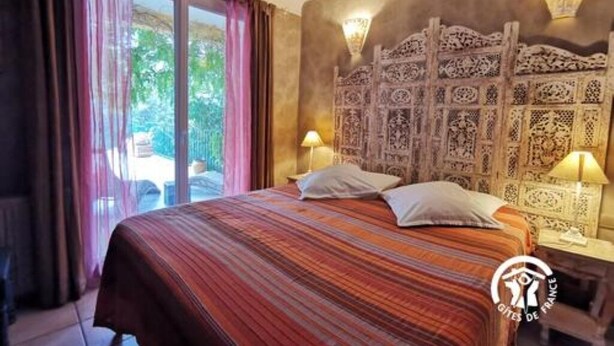A hotel room with a large bed, a decorative headboard, and two bedside lamps.