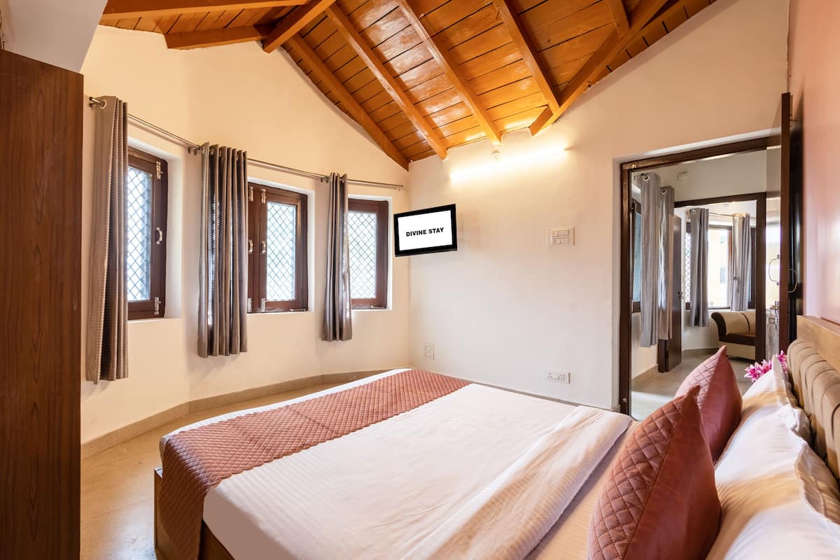 A bedroom with a bed, wooden ceiling, and a sign that reads "DIVINE STAY".