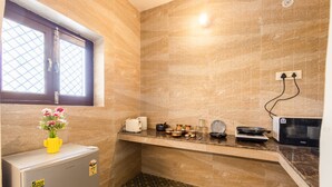 Una cocina compacta con ventana, refrigerador, microondas y pileta.